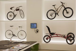 4 bikes displayed on a whote wall in alcoves with a monitor and headphones