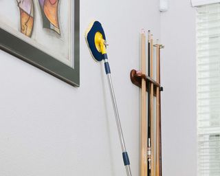 chomp mop being used on a wall with framed artwork and snooker cues