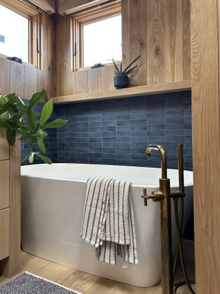 bathroom with white bathtub and surrounding blue tiles and wooden walls and accents