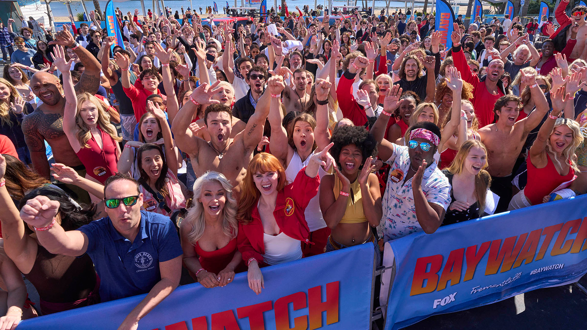 Fans line up for Fox's Baywatch open casting call in 2026. Lots are in red swimwear and lifeguarding gear.