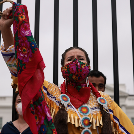 A demonstrator holds up her fist in front of the White House during a climate march in honor of Indigenous Peoples&rsquo; Day at on October 11, 2021 in Washington, DC. Activists organized the march to the White House to demand that U.S. President Joe Biden stop approving fossil fuel projects and declare a climate emergency, ahead of the United Nations climate summit in November.