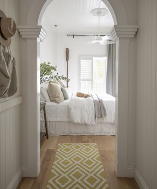 A hallway carpet idea with a yellow runner leading into a white bedroom