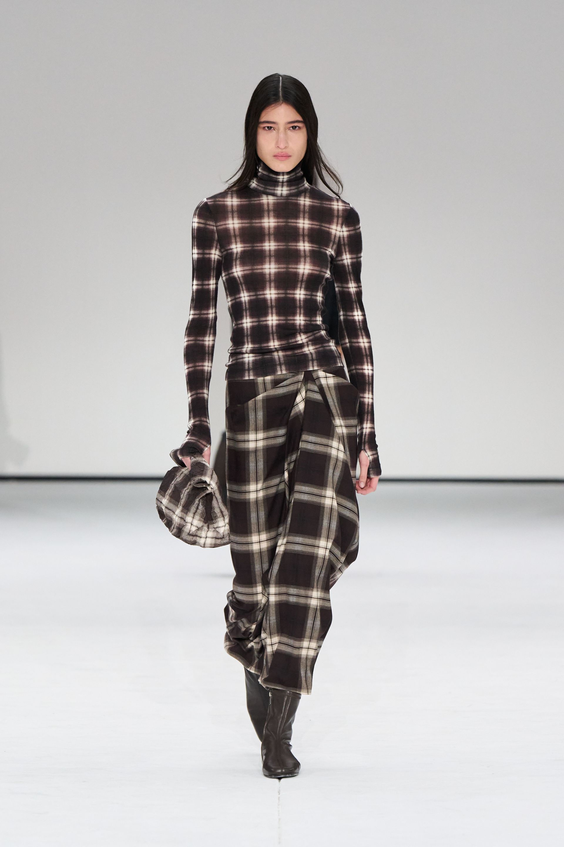 A woman wears a plaid shirt, plaid skirt at the cos show.