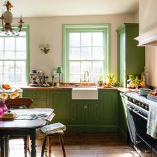 traditional kitchen with green cabinetry and wood work, cream walls and wooden floors in a 17th-century london maisonette