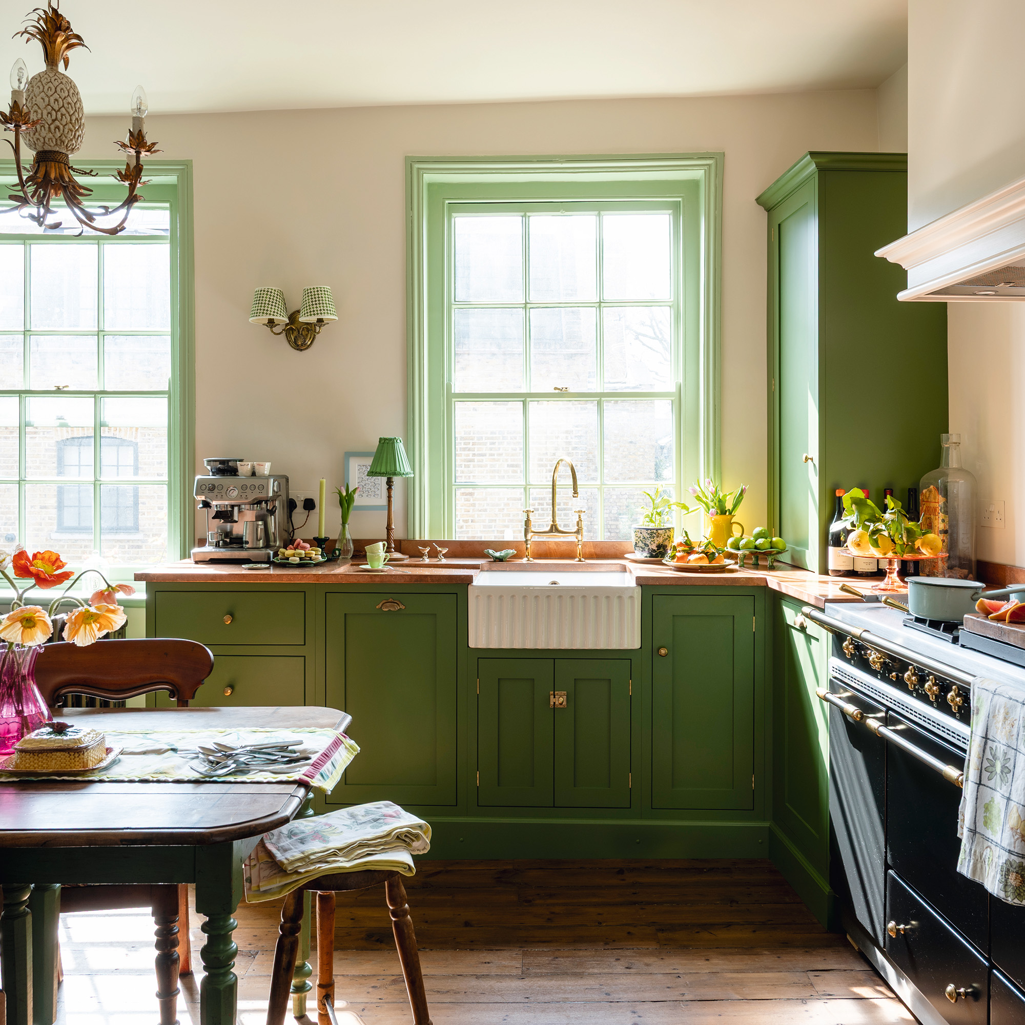 traditional kitchen with green cabinetry and wood work, cream walls and wooden floors in a 17th-century london maisonette