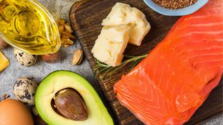 Collection of foods rich in healthy fats, including salmon, avocado, butter, and olive oil