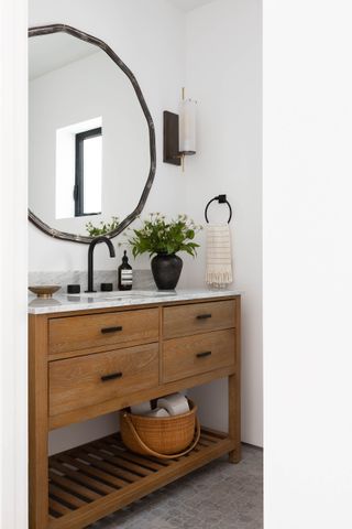 A small guest bathroom with storage baskets under the vanity