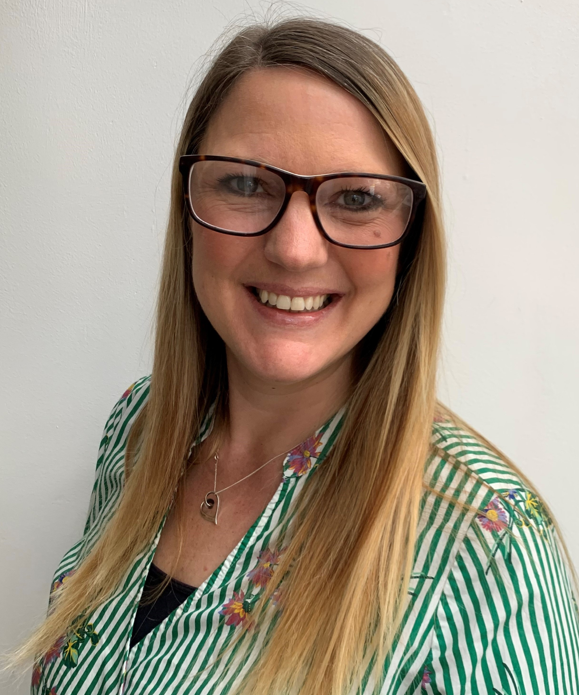 female with long blond hair, glasses wearing green and white blouse