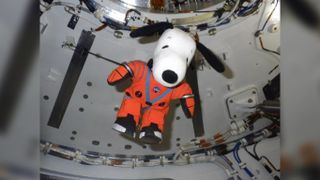 Snoopy floating and wearing NASA orange spacesuit