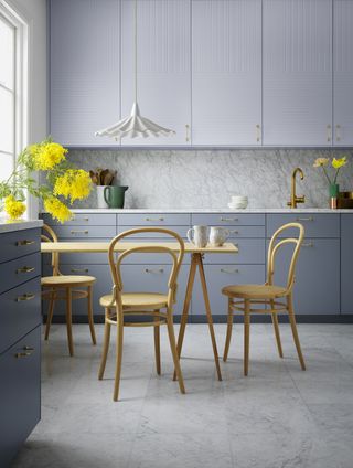 grey kitchen with contemporary cabinetry, small dining table and chairs, marble style floor tiles, brass tap, white pendant light