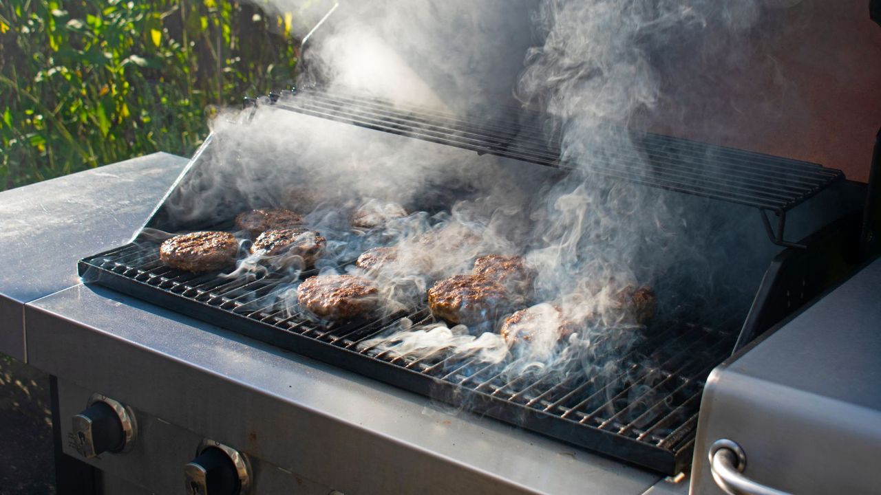 An example of &#039;is grill smoke unhealthy&#039;, burgers grilling on a gas grill and making lots of smoke