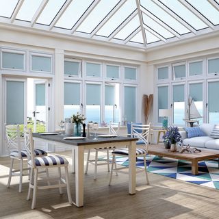A conservatory with blue blinds, a dining table and a geometric rug