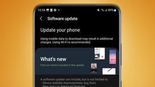 En Samsung-mobil mot en orange bakgrund som visar en programuppdatering som installeras.