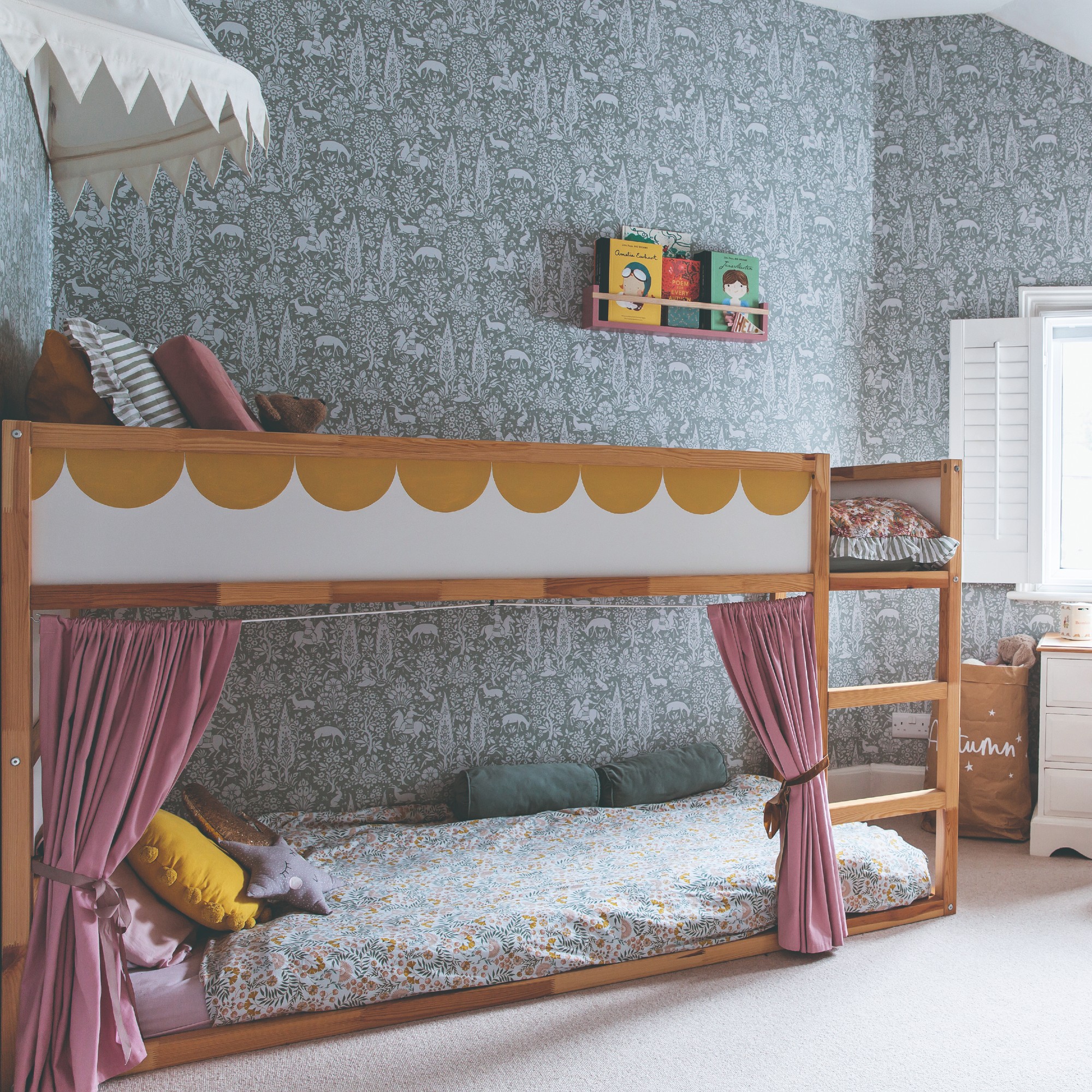 A shared children&#039;s bedroom with a scalloped bunk bed and Morris &amp; Co. wallpaper on the walls
