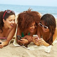 young women on beach with cell phones