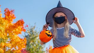 Young girl dressed as a witch for Halloween wearing a face mask