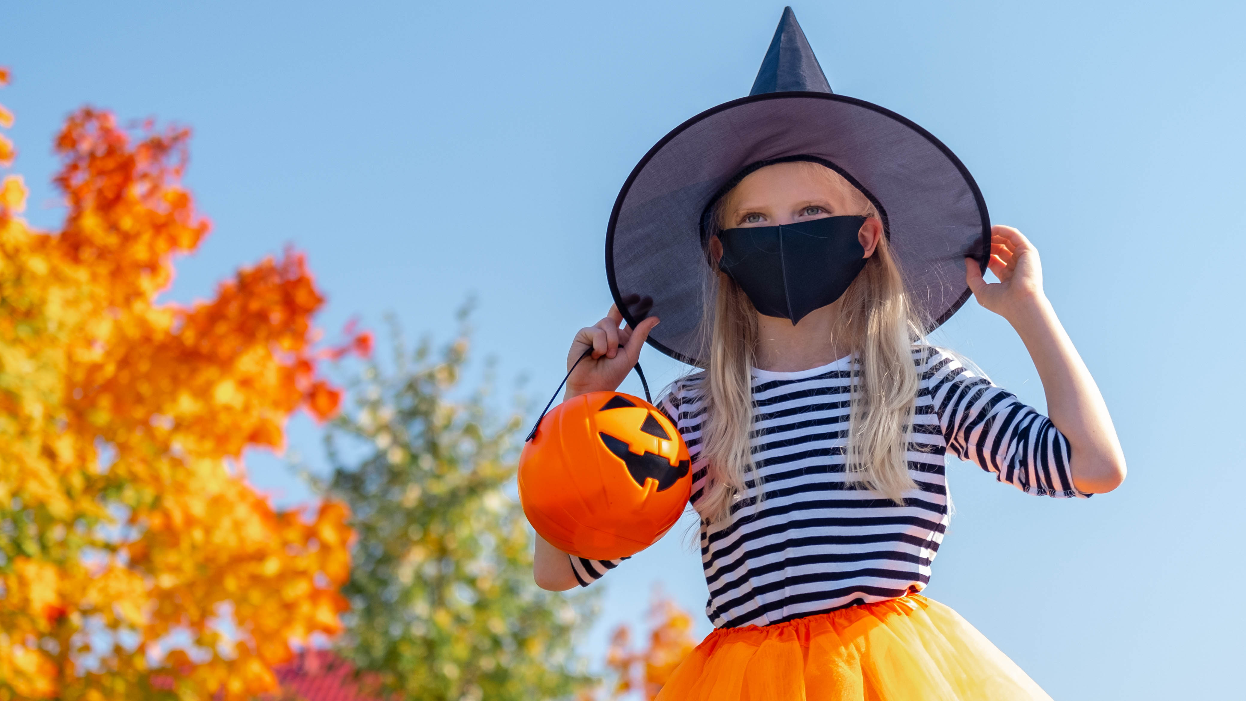 Young girl dressed as a witch for Halloween wearing a face mask