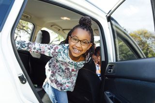 Smiling girl standing in car during road trip