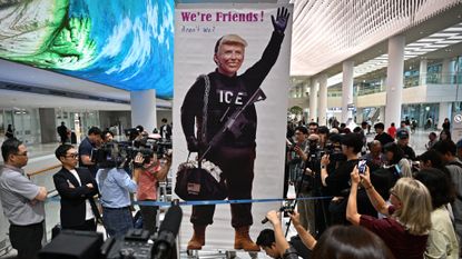 South Korean holds up image of President Donald Trump as workers detained in Georgia immigration raid land at Seoul airport