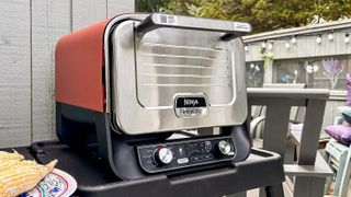 A Ninja Woodfire Outdoor Oven sitting on a table on someone's decking in the garden