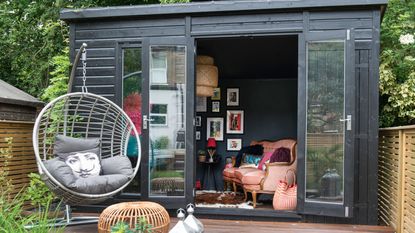 Garden grey shed beside a decked area with suspended circular chair