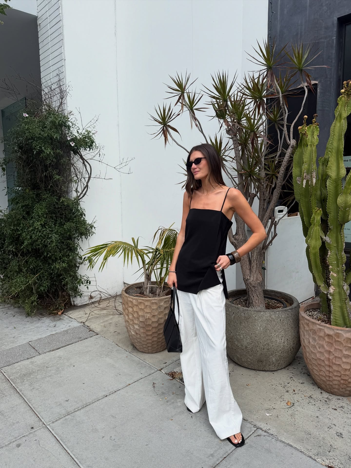 Woman in black tank top and white pants.