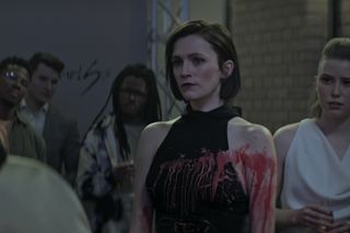 Kate wearing a black outfit, covered in red paint