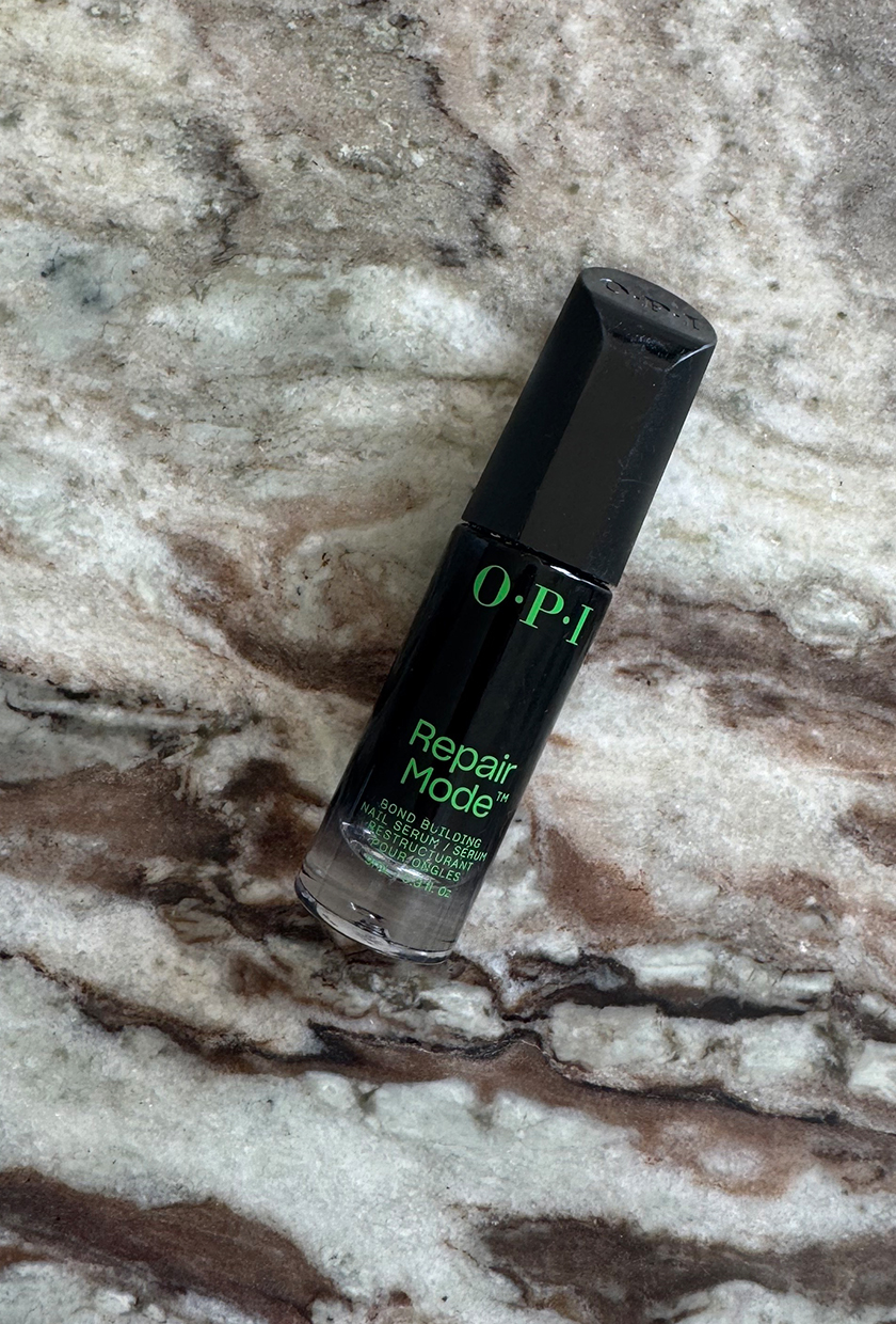 A bottle of OPI Repair Mode on a marble table