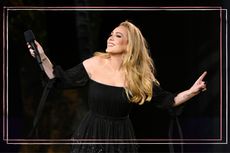 Adele on stage in a black dress holding a microphone