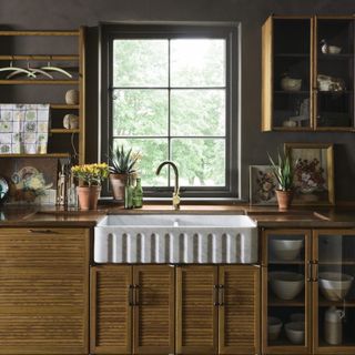 kitchen sink area with wooden cupboards and dark brown walls