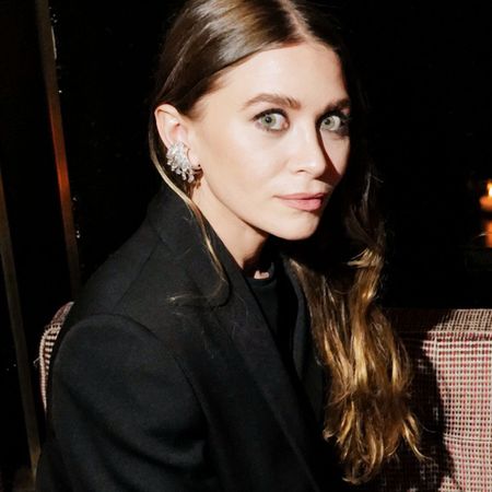 a brunette Ashley Olsen at an event wearing statement earrings and a black blazer