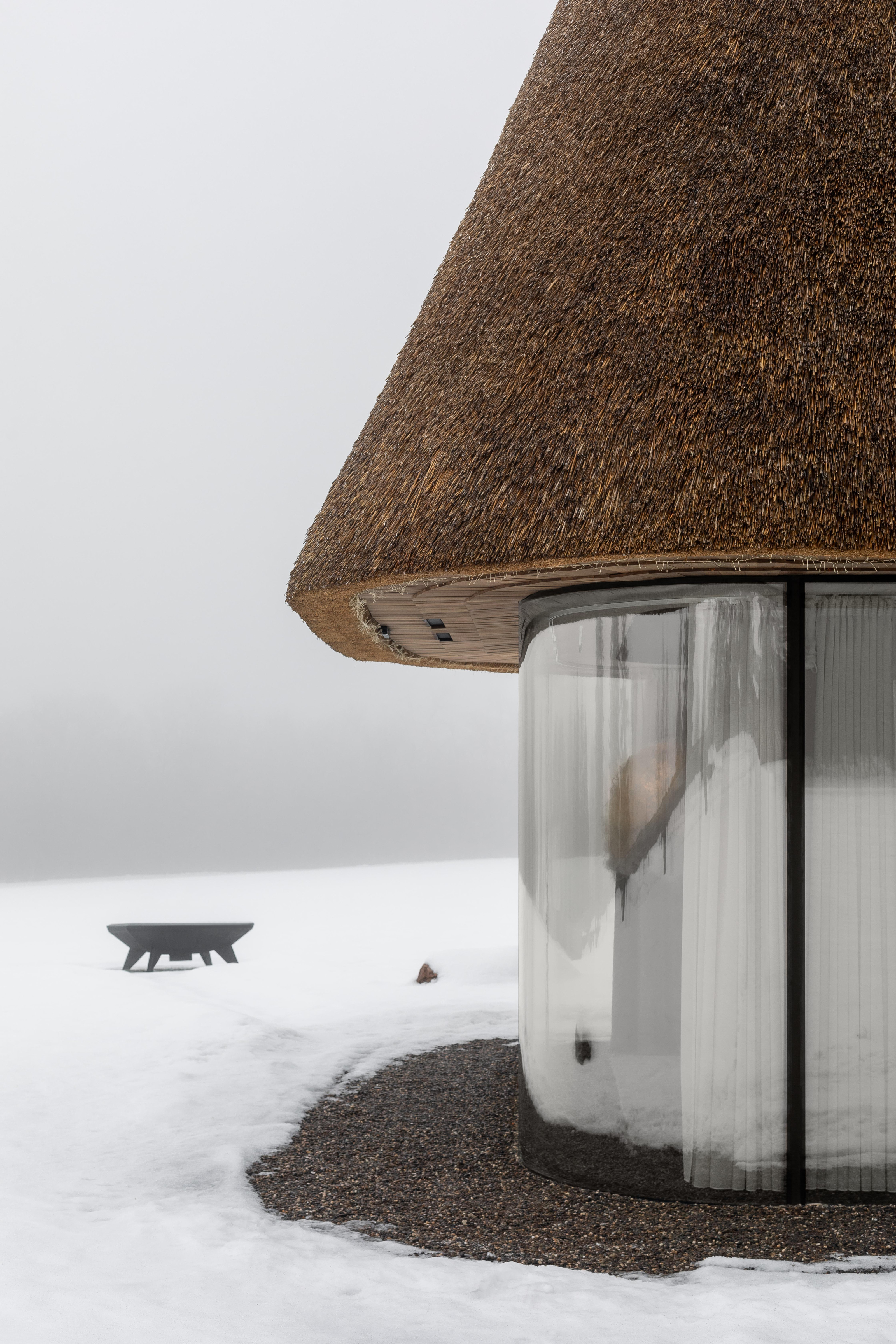 The curved glass facade and neatly trimmed thatch roof