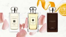 A collage featuring three of the best Jo Malone London perfumes per our beauty team, including the Pomegranate Noir, Lime Basil & Mandarin and Myrrh & Tonka colognes/ all featured on a white and grey marbled background with pink rose petal and an orange, half peeled. 