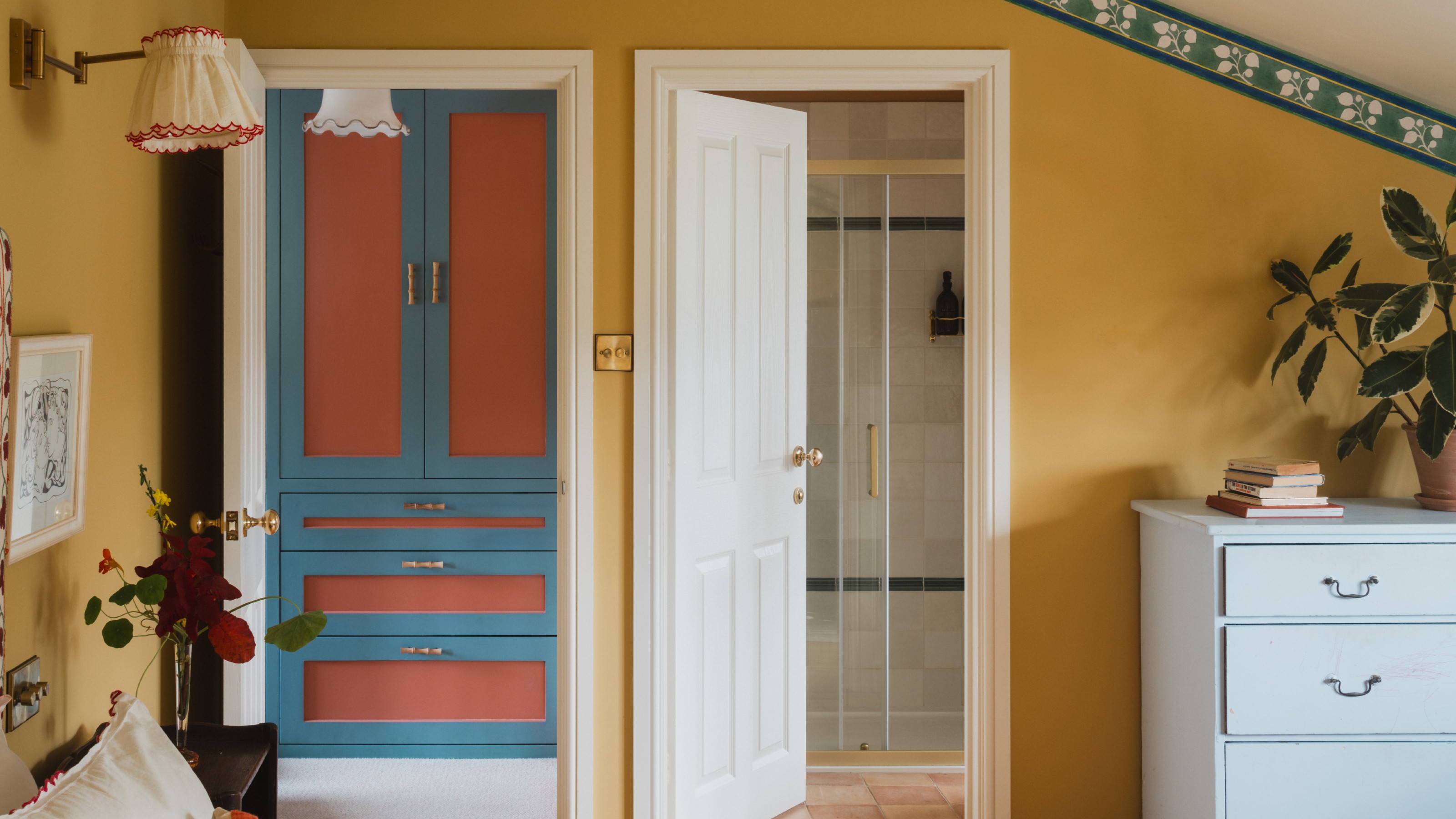A yellow-painted bedroom with a green floral border and an en suite bathroom