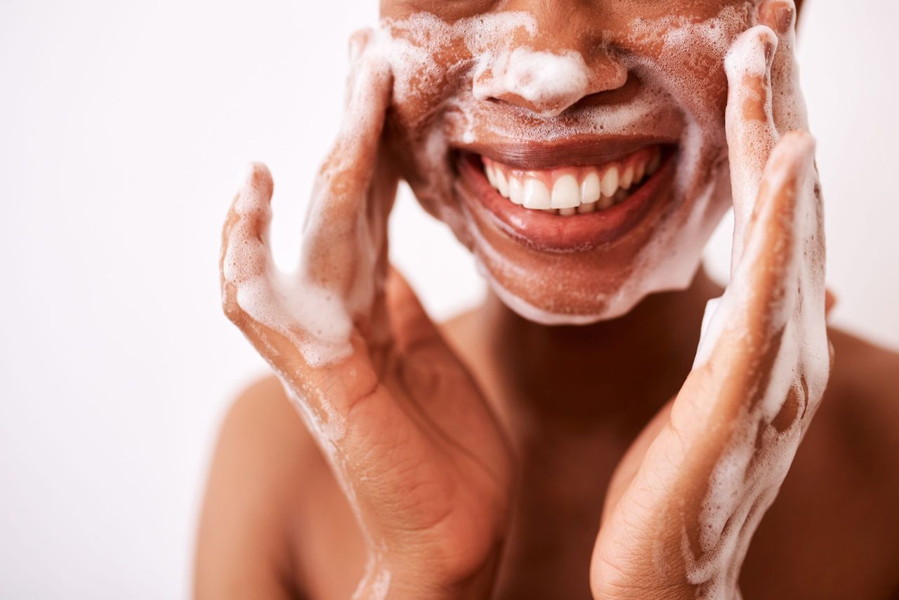 Studio shot of a woman washing her face against a white background