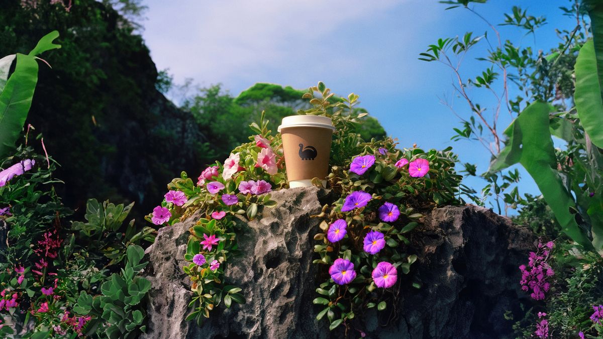 Coffee cup with the De-extinction logo on a natural floral background