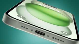 La parte inferior de un iPhone 15 sobre fondo verde que muestra su puerto USB-C y su micrófono
