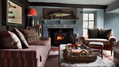 small cabin style living room with a delft tile fireplace, log burner, pattern mixed furniture and a large fish wall art above the fireplace