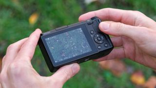 Ricoh GR IV compact camera held in a pair of hands