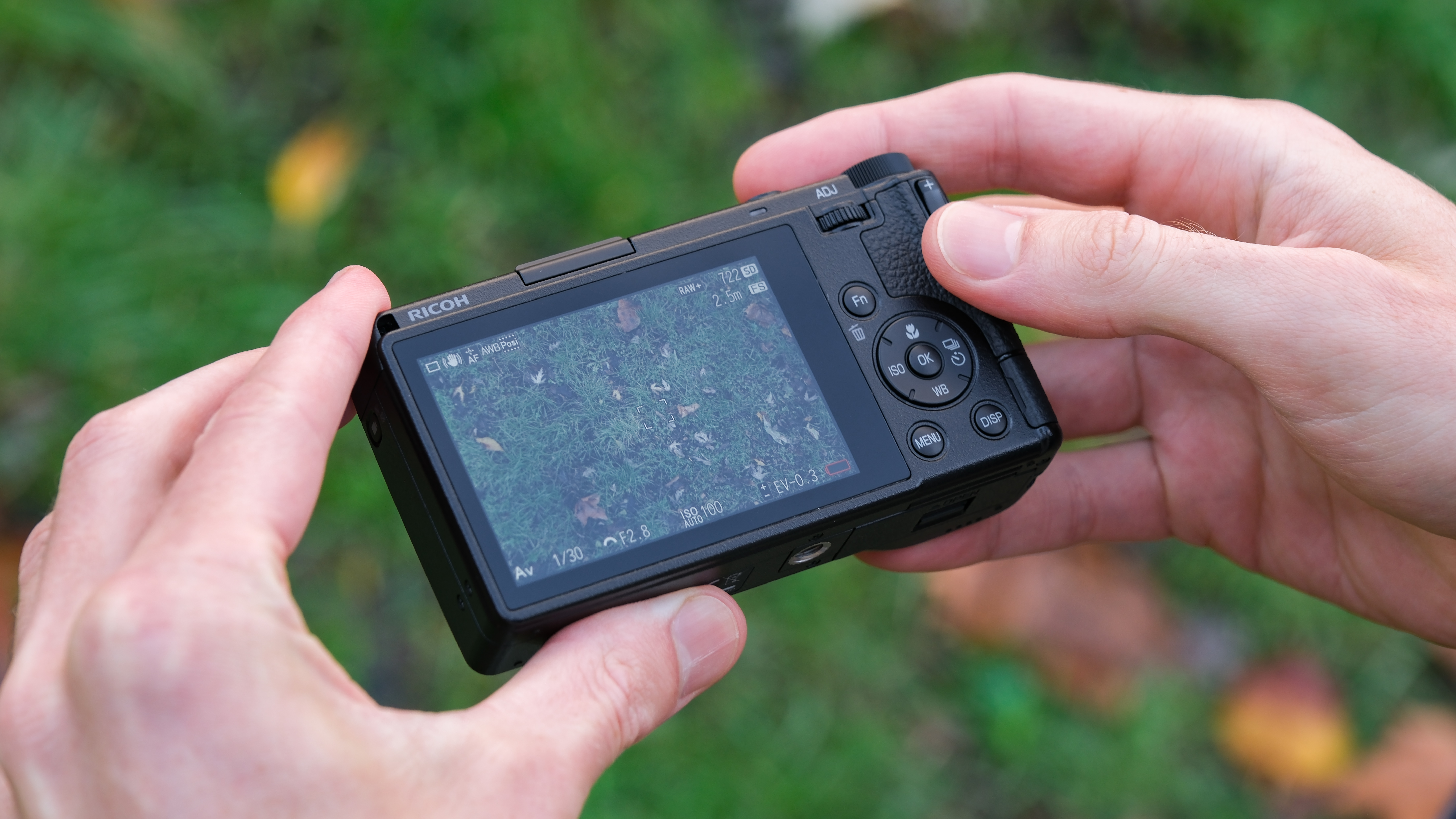 Ricoh GR IV compact camera held in a pair of hands