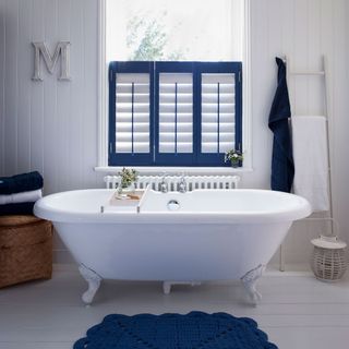 bathroom with white wall and wooden floor and blue window shutter and blue rug