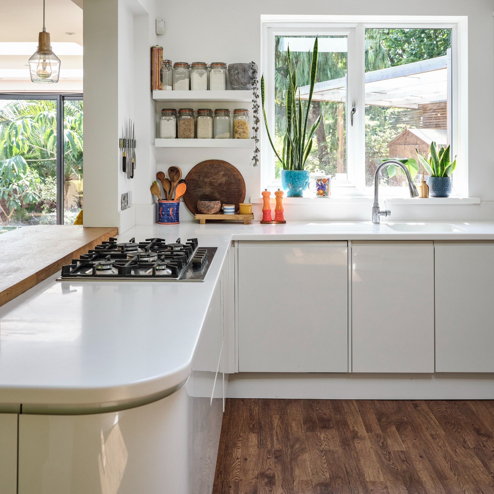 A white kitchen with wooden floors and white glossy cabinets
