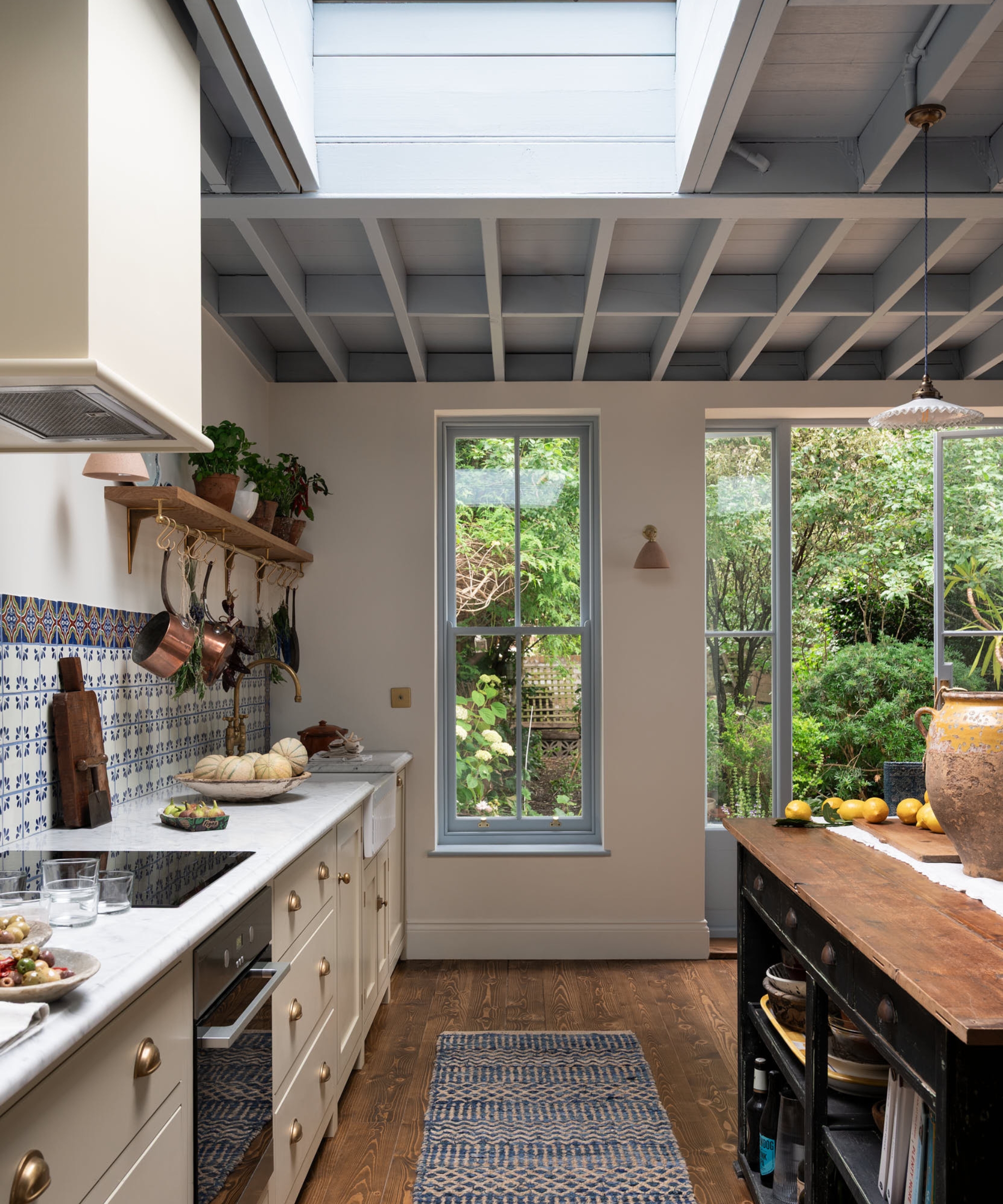 A large kitchen with cream cabinets, white walls, and a blue ceiling