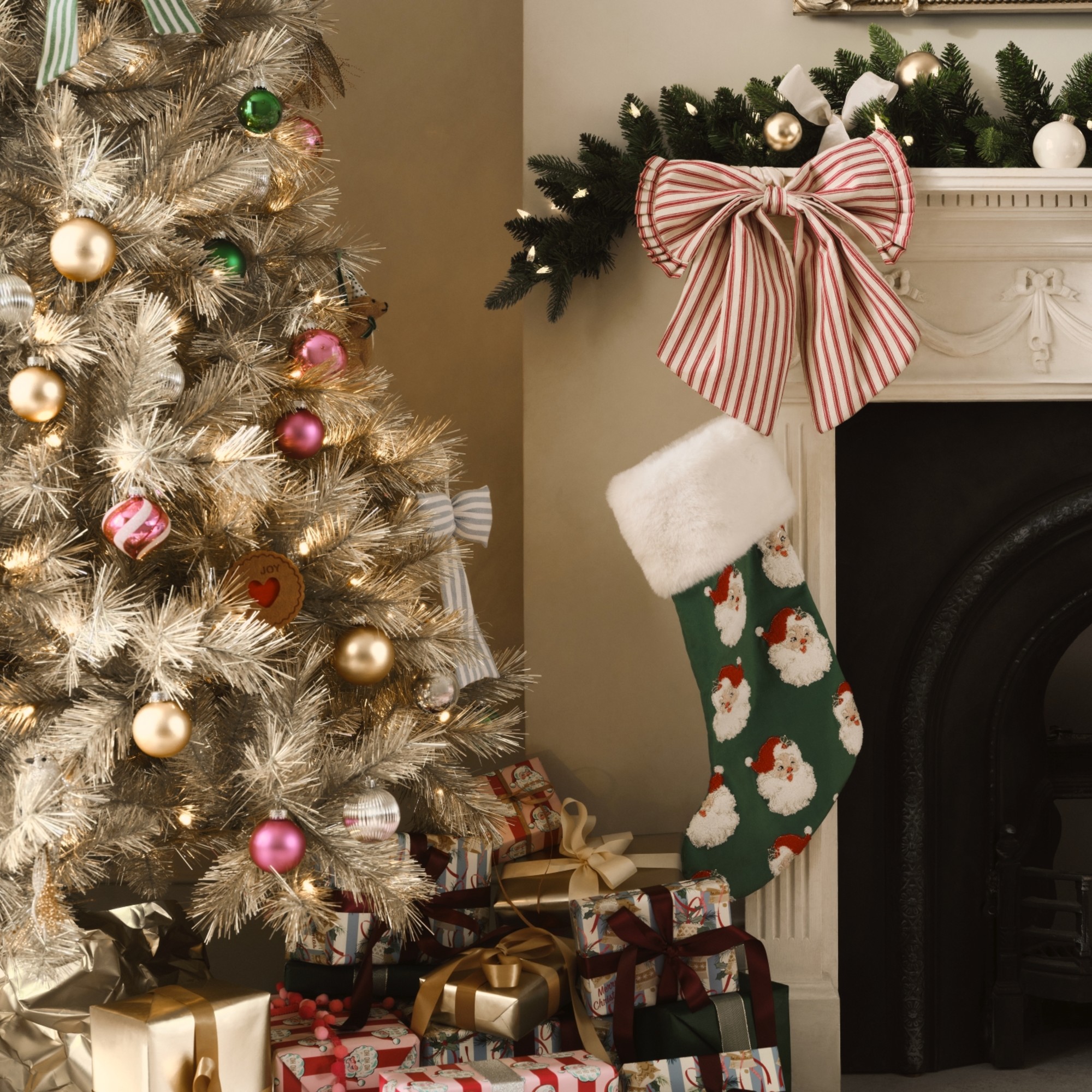 A gold-tone Christmas tree next to a fireplace, decorated with decorations from the John Lewis Heirloom Splendour range