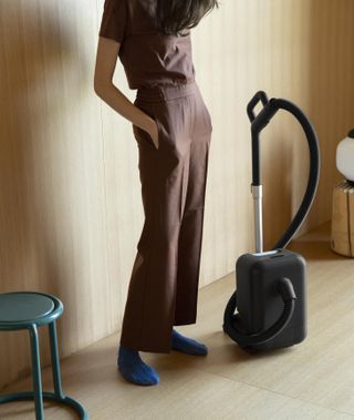 compact vacuum cleaner on the floor next to a woman