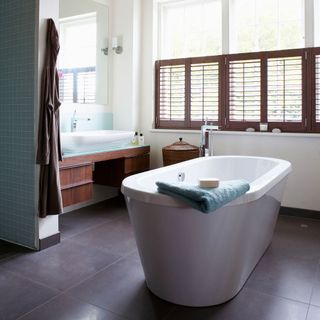 bathroom with white bathtub and grey tile flooring