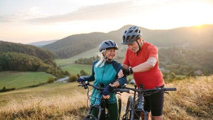 Senior couple on bike ride checking performance and route on smartwatch