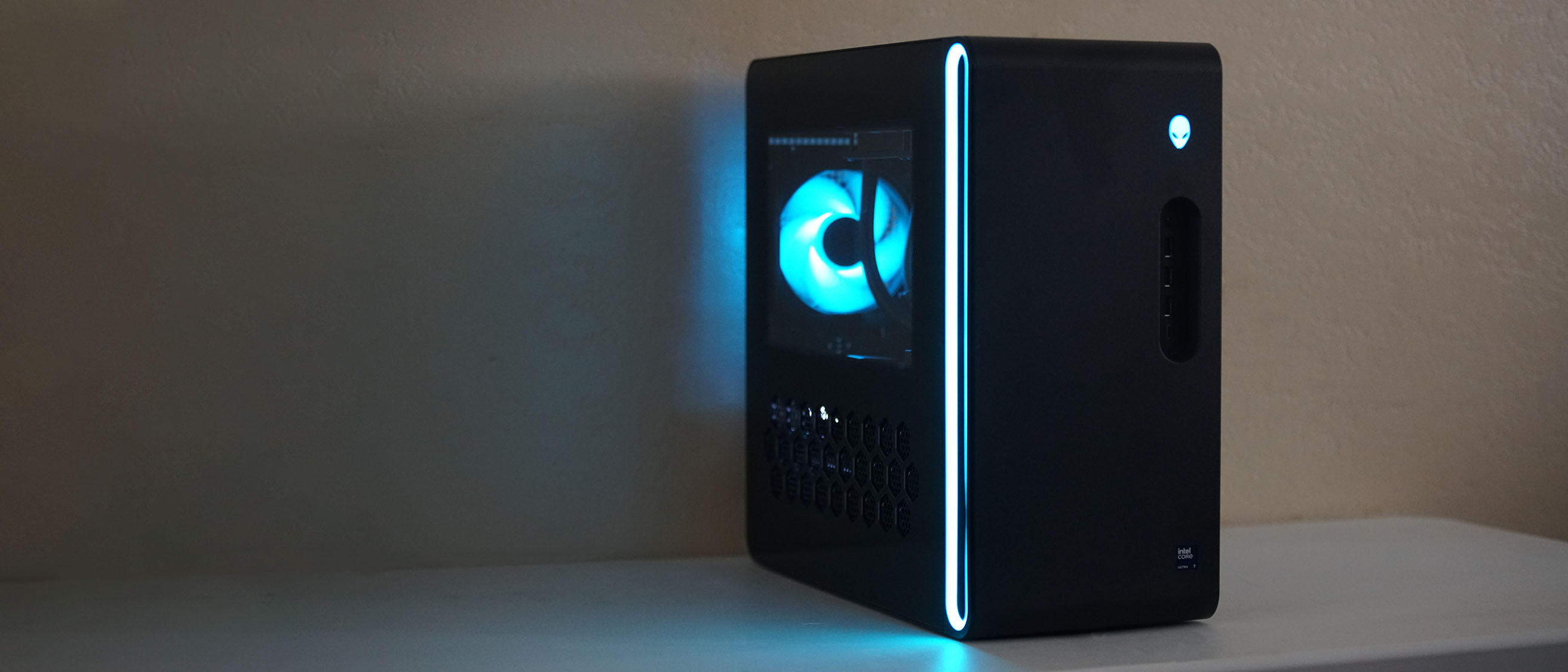 An angled wide-angle view of the Alienware Aurora gaming desktop on a desk in a darkened room