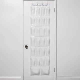 An over the door shoe organizer has clear plastic pockets on a white canvas base
