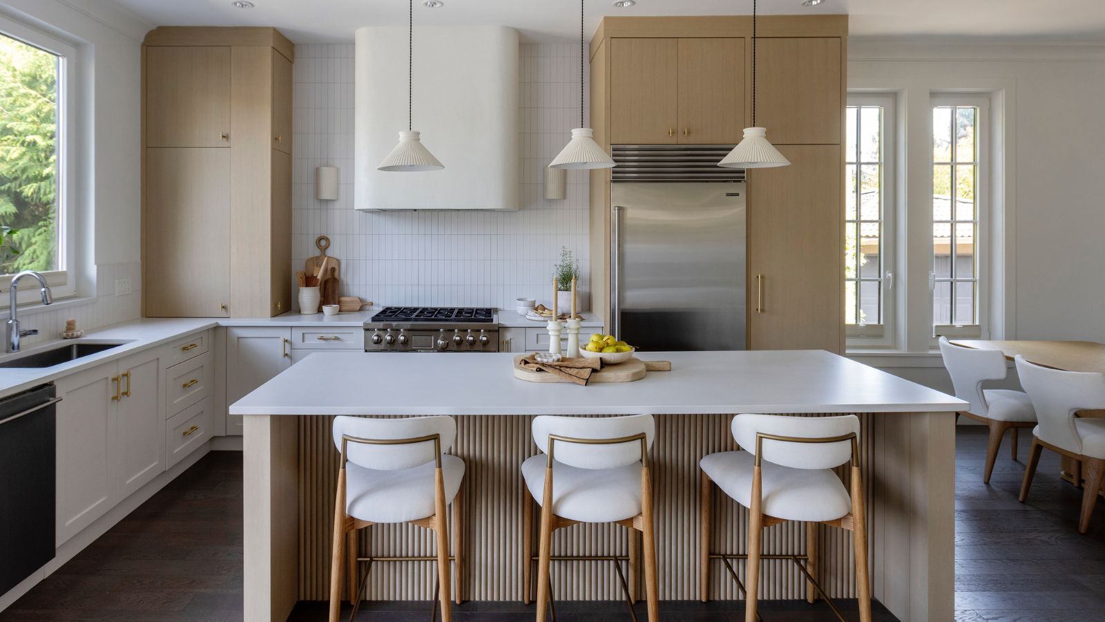 A wood and white kitchen with fluted details and a curved range hood